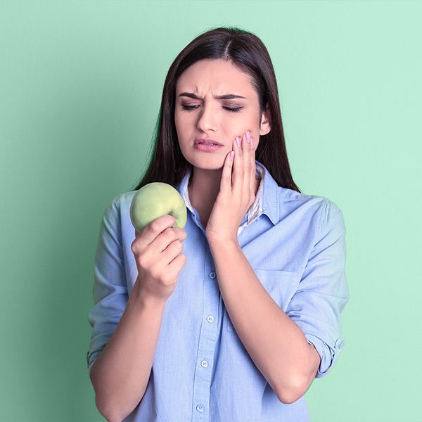Woman looking at apple and holding jaw